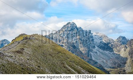 group of hikers admires view from Kasprowy Wierch on Swinnica mountain in Hight Tatras, Poland