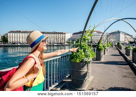 Young female traveler standing on the pedestrian bridge in the center of Geneva city in Switzerland. Happy vacation in Geneva city