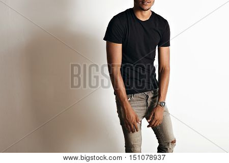 Mockup shot of a plain black cotton short sleeve t-shirt on an athletic black or latino man in a studio with white walls