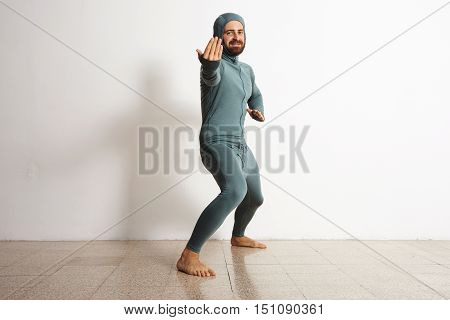 Happy smiling bearded sportsman wearing snowboarding thermal baselayer suite from merino wool and acts like a ninja, looking in camera, isolated on white