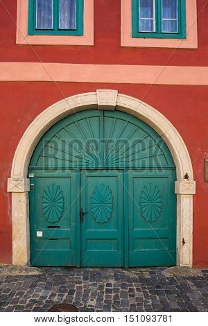 Very old wood green doors red wall and two windows
