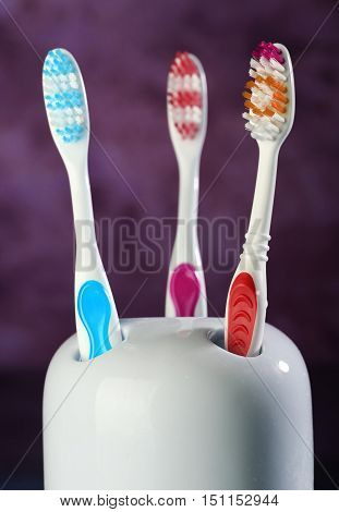 Three colorful toothbrushes in holder with background