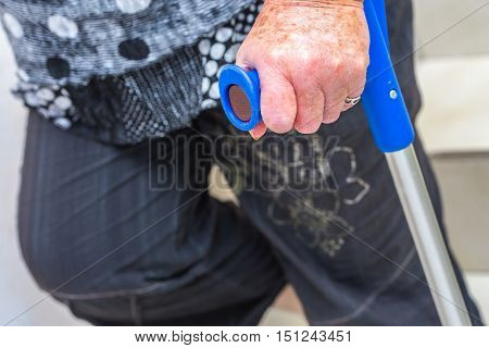 close up on the hand of an elderly disabled woman holding a crutch