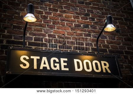 Stage door sign lit by spotlights at theatre venue