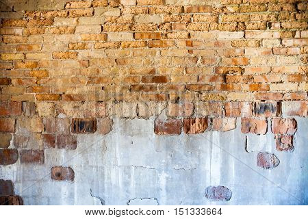 Old brick wall with the damaged plaster.