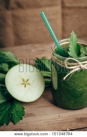 Green smoothie with celery and apple on rusic wooden table, vertical frame