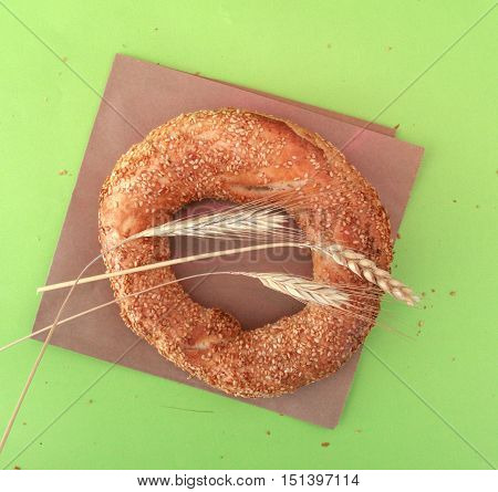 Turkish bagel simit and wheat ears on green.top view