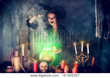 Attractive witch conjures in the wizarding lair. Fairytales. Halloween.