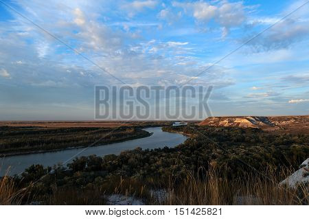 Golden sunset on the river. Autumn landscape. Beautiful clouds and hills.