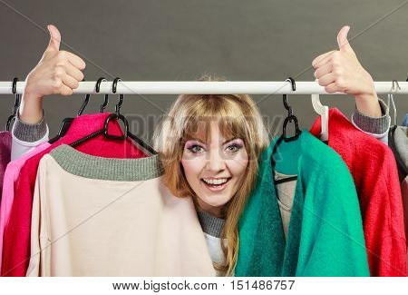 Pretty happy woman with clothing from wardrobe. Young undecided shopper girl bought new clothes. Shopping sale and thumb up gesture concept.