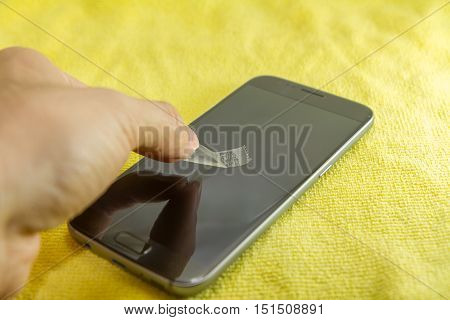cleaning mobile phone screen by adhesive clear tape. Before apply the smart phone screen protect flim