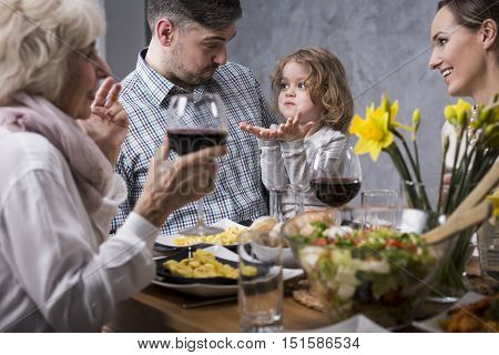 Close-up of a father and his little son having fun at the table during a family dinner