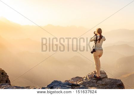 A woman is taking photos of Al Hajar Mountains in Oman at sunset