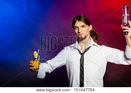 Liquor drinking party flair bartending concept. Tapster enjoying alcohol beverage. Young male barman prepares cocktail with orange juice.