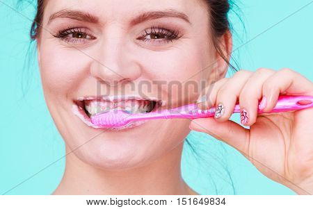 Woman brushing cleaning teeth. Girl with toothbrush close up. Oral hygiene. Blue green background