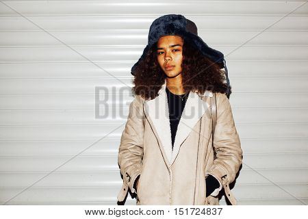 young pretty african american girl teenage outside on street, looking like real junky, social issues concept, red eyes, bum stupid hat, fashion hipster lifestyle people close up mudy