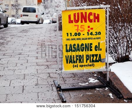 Lunch specials at a pizzeria in Sweden with text in Swedish. The text contains a description of the offer costing SEK 75 valid at 11:00 to 14:30 contains lasange or pizza with the exception of special pizzas including butter bread salad drinks and coffee.