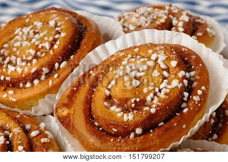 Close-up of a heap of cinnamon rolls iin tins of greaseproof paper.