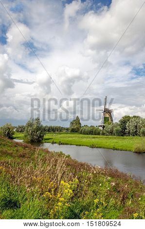 Picturesque image of a restored historic Dutch windmill originally built in 1792. It is a cloudy and windy day in the end of the summer season in the Netherlands.