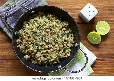 Quinoa salad with lentils and parsley in bowl photographed overhead on wood with natural light (Selective Focus Focus on the top of the salad)