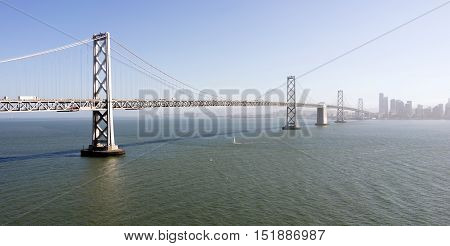 Vehicles and boats move along above and below the Bay Brdige in San Francisco