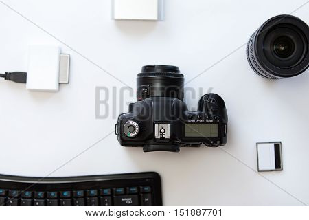 White desk with a professional camera and accessoires on it. Top view
