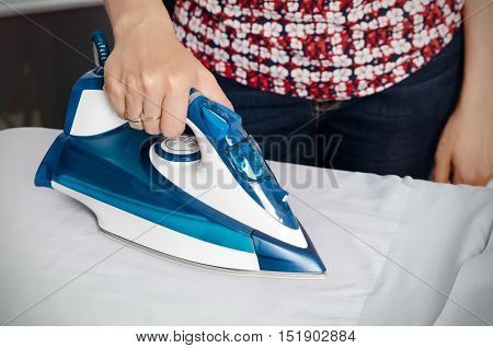 Woman Irons Clothes On Ironing Board With Steaming Iron