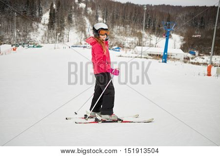 Teenage girl equipped for skiing on snowy slope at ski resort.