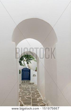 Arched doorways leading to a blue door. Traditional architecture of local villages at Paros island in Greece.