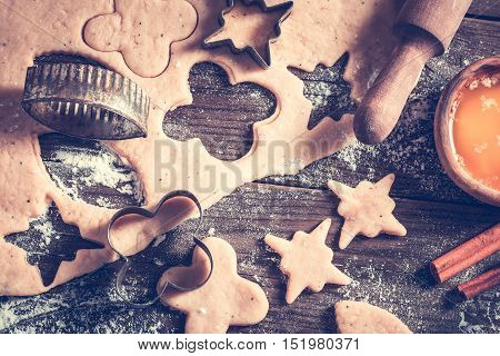 Various shapes cookie cutters and dough on table. Baking concept in dark colors top view. Toned.
