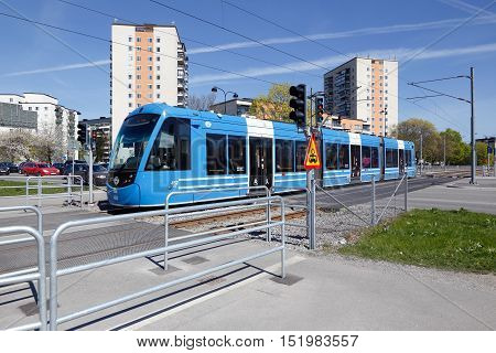 Solna, Sweden - May 6, 2016: Blue tram of class A35 on the Tvarbanan line at the road crossing with Gransgatan.
