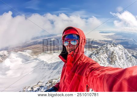 Selfi Male Mountaineer In Snowy Mountains, Wearing A Helmet With A Backpack.