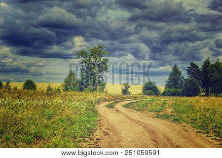 Summer Rural Landscape With Storm Sky Country Road Away Trees And Yellow Wheat Field