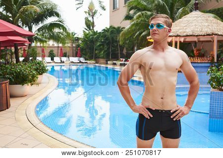 Portrait Of Confident Pround Young Man Standing At Hotel Swimming Pool