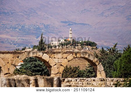 Mosque On A Hill Seen From Umayyad Ruins With Mountains In The Background On A Sunny Day At Anjar, B