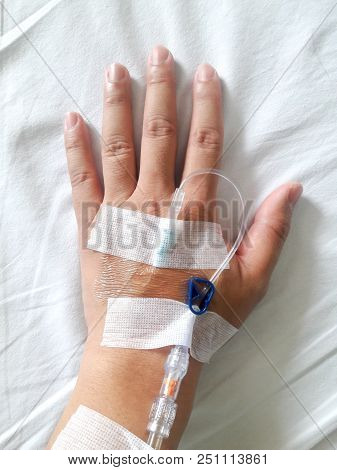 Patient Hand With The Tube Of Normal Saline Infusion On White Cloth Background