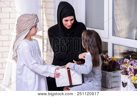 Arabic Mother Giving Gift To Her Boy And Girl.muslim Family.