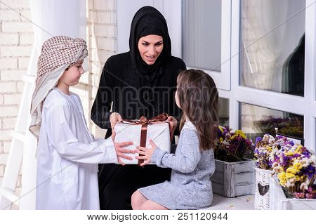 Arabic Mother Giving Gift To Her Boy And Girl.muslim Family.