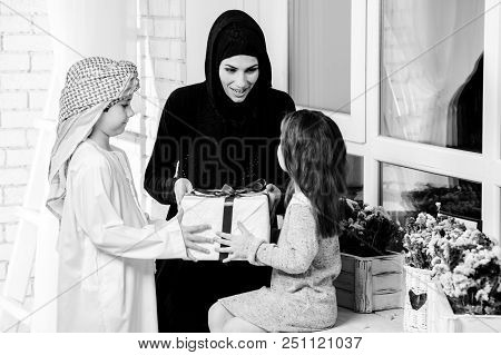 Arabic Mother Giving Gift To Her Boy And Girl.muslim Family.black And White.