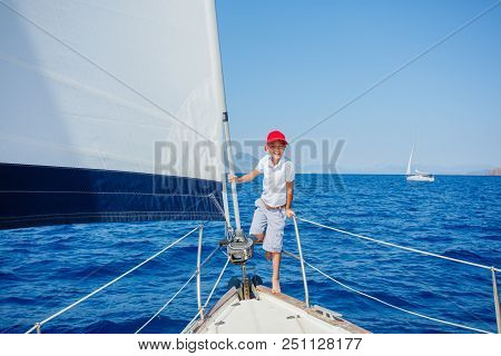Cute Boy On Board Of Sailing Yacht On Summer Cruise. Travel Adventure, Yachting With Child On Family