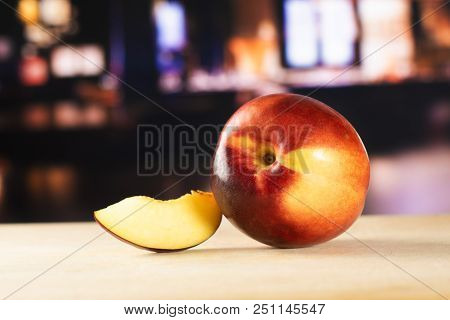 Group Of One Whole One Slice Of Ripe Deep Red Nectarine With Restaurant In Background