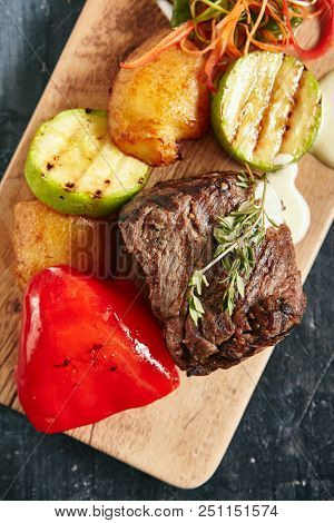 Hot Grilled Beef Tenderloin Steak, Barbecue Sirloin Meat on Wooden Background with Bbq Vegetables Top View. Macro Photo of Fresh Juicy Deep Fried Veal Grillsteak Close Up