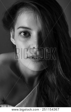 A Beautiful Brunette Girl With Hair Thrown Over One Side Looks Into The Frame. Vertical Photo