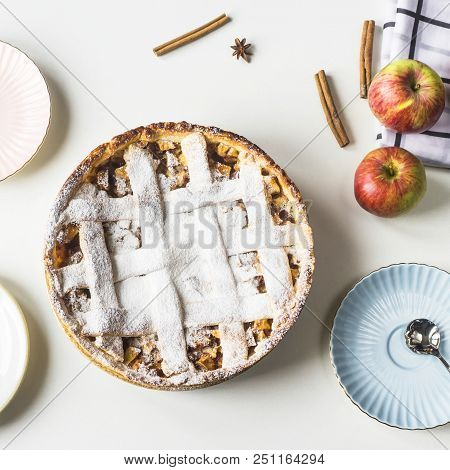 Homemade Apple Pie Sprinkled With Powdered Sugar In Female Hand On A White Table Next To Apples, Cin