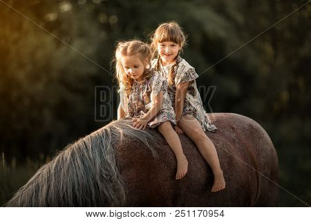Little Sisters With Horse At Summer Cloudy Evening