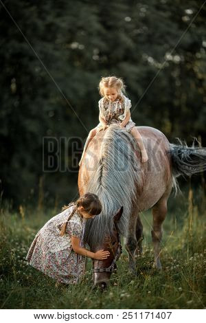 Little Sisters With Horse At Summer Cloudy Evening