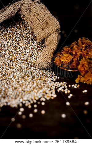 Close Up Of Raw  Dried Grains Of Pearl Millet With Jaggery Or Gud On A Wooden Surface In Drak Gothic