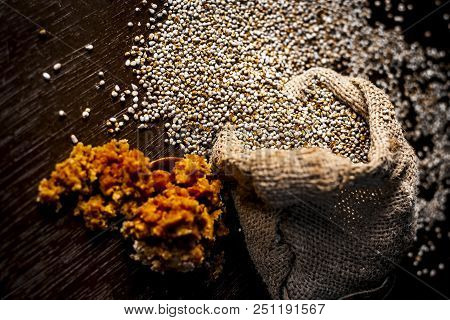 Close Up Of Raw  Dried Grains Of Pearl Millet With Jaggery Or Gud On A Wooden Surface In Drak Gothic
