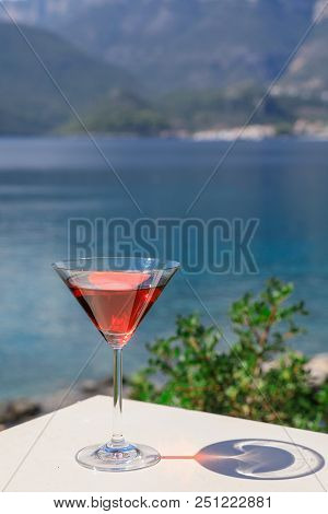 A Glass Of Red Martini On The Seascape Background. Vertical. Close Up.