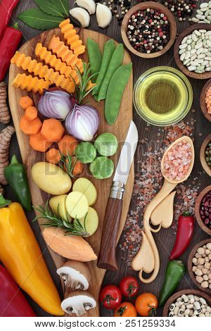Healthy food concept with fresh vegetables, herbs, spice, pulses, olive oil and himalayan salt in a wooden lovespoon. Super foods  high in antioxidants, anthocyanins, minerals and vitamins.